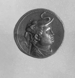 Moneda acuñada por Ptolomeo I (367 a. C. - 283 a. C.) que muestra a Alejandro Magno (356 a. C. - 323 a. C.) con tocado de elefante y cuerno de carnero (plata)